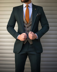 attractive man in tailored suit posing in front of background