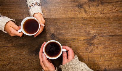 Cups of black tea in the hands of men and women. on a wooden background. with copy space. top view