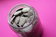 Nonpareils Chocolate Candy In Glass Jar On A Pink Background