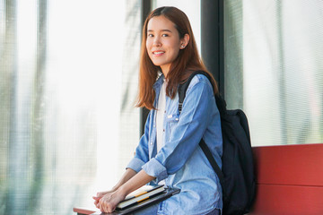 Canvas Print - Portrait of asian female colleges student holding textbook in her hands and standing outdoors at university campus