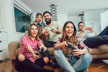 Group of friends play video games together at home, having fun.