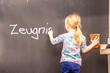 Cute little girl writing Zeugnis on chalkboard - Translation Testimony
