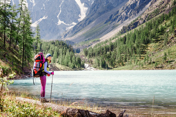 Wall Mural - girl hiker standing on a rock and looking at the lake in Altai mountains