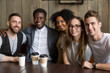 © fizkes - Portrait of multicultural millennial young friends looking at camera, happy multiracial people group having fun in coffeehouse together, diverse african and caucasian students bonding at cafe meeting