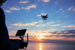 © lzf - Silhouette of remote control a flying drone which taking photo over sunrise sea