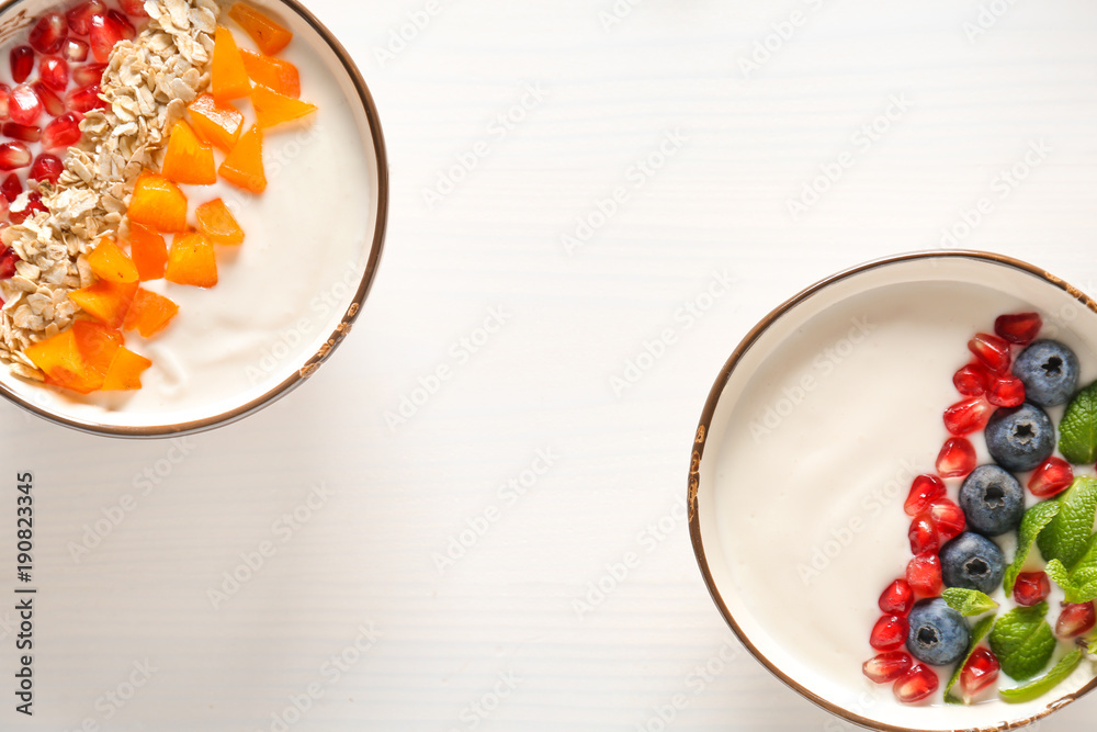 Yogurt with fruits in dishes on wooden table