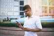 © Dusko - Positive and handsome Afro American man standing in front of huge modern business building smiling and talking on cell phone