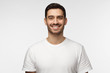© Damir Khabirov - Close up portrait of smiling handsome man in white t-shirt looking at camera, isolated on gray background