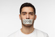 © Damir Khabirov - Close up shot of young man with taped mouth with shhh text on it