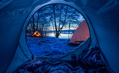Wall Mural - camp by the lake with campfire at dusk in winter