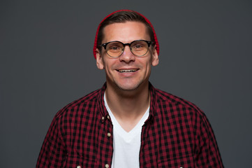 Wall Mural - Portrait of young stylish hipster guy wearing glasses looking at the camera on gray background