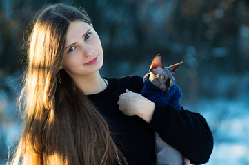 Young pretty girl with her pussy in her arms. In the winter park on a bright day. Cat breed swiss