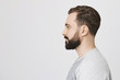 © Cookie Studio - Profile portrait of handsome bearded adult european man with trendy haircut, standing over gray background. Hairdresser makes photo of new haircut he did for visitor to post it on site