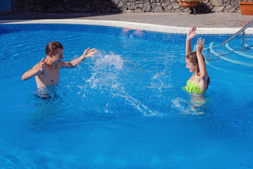 Wall Mural - boy and girl having fun in swimming pool