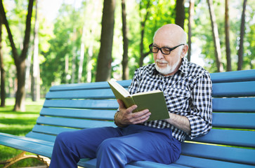 Elderly man in casual reading outdoors