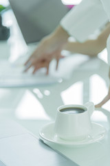 A coffee cup with white plate on the office desk.