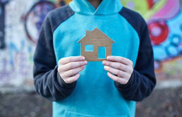 homeless boy holding a cardboard house