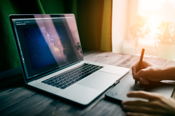 Fototapete - Man freelancer is working using laptop computer and graphics tablet at home office. Professional occupation workplace