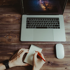 Fototapete - Man is writing on draft notepad and using laptop computer at home office. Freelance lifestyle workplace