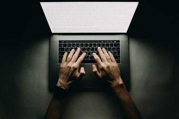 Fototapete - Man is working typing use laptop computer at dark night. Writer flat lay top view workplace