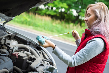 Wall Mural - Girl checks the oil in the car's engine