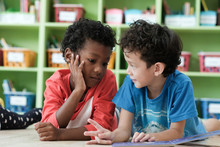 American And African Boys Are Reading Together With Happiness In Their Kindergarten Classroom, Kid Education And Diversity Concept