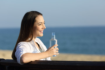 Wall Mural - Woman holding a bottle of water on the beach