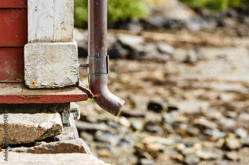 Fotografia, Obraz Thin drainpipe on cottage wall, rocks background
