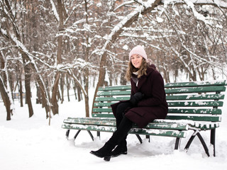 Cute young woman smiling on the bench in winter