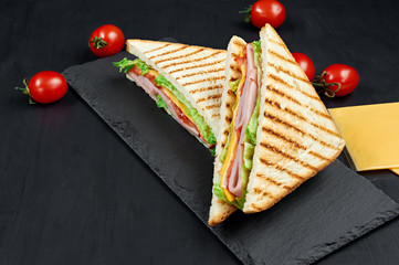 Wall Mural - Sandwich with ham, cheese, tomatoes, lettuce, and toasted bread. Above view isolated on black background.