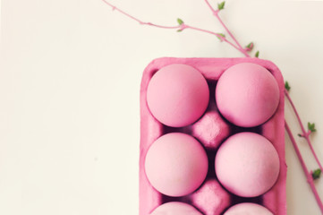 Wall Mural - Pink easter eggs in pink box, on white table, decorated with pink branches; easter background