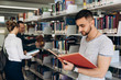© IVASHstudio - Thoughtful boy looks like a student standing with book in the library of a university