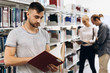 © IVASHstudio - Thoughtful boy looks like a student standing with book in the library of a university