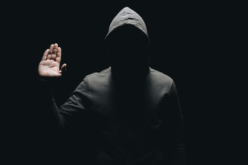 unrecognizable man in hoodie showing palm isolated on black