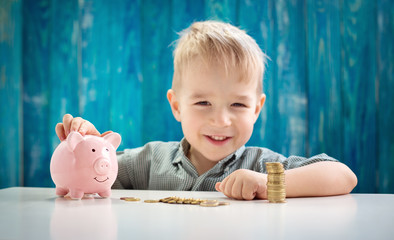 three years old child sitting st the table with money and a piggybank