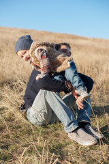 Wall Mural - Child in the hands of his father in the autumn field