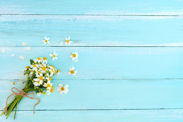 Beautiful bouquet of white wildflowers on blue wooden background.  Concept flowers of spring, top view and border design