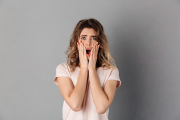 Shocked worried woman in t-shirt holding her cheeks