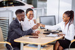 © alfa27 - happy African couple and female seller sit at table and make a deal for sale of car