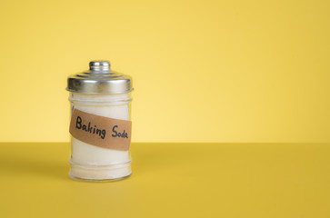 Jar of baking soda with text space against yellow background