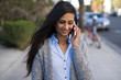 © blvdone - Young Indian woman walking street talking on cell phone
