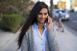 © blvdone - Young Indian woman walking street talking on cell phone