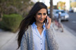 © blvdone - Young Indian woman walking street talking on cell phone