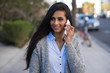 © blvdone - Young Indian woman walking street talking on cell phone