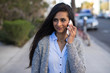 © blvdone - Young Indian woman walking street talking on cell phone