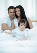 © ASDF - Portrait of a joyful family sitting on the bed at home
