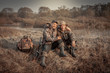 Hunter men friends resting in rural field during hunting period symbolizing strong friendship