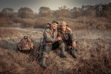 hunter men friends resting in rural field during hunting period symbolizing strong friendship