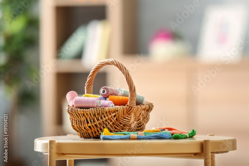 Fotomural  Wicker basket with sewing and mouline threads on table indoors