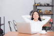 © N_studio - Beautiful young asian woman with laptop stretch and exercise relax after work success, modern office with copy space, freelance business concept.